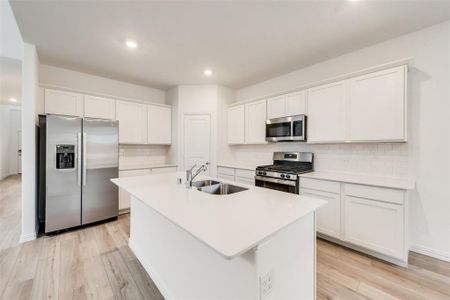 Kitchen with appliances with stainless steel finishes, backsplash, a kitchen island with sink, and sink