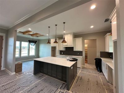 Kitchen with white cabinets, a kitchen island, hanging light fixtures, and tasteful backsplash