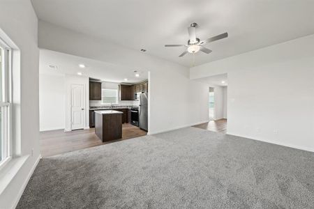 Unfurnished living room featuring dark colored carpet, sink, and ceiling fan