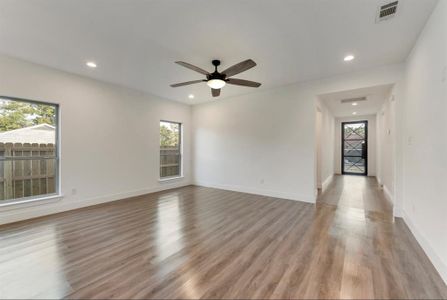 Empty room with ceiling fan, a wealth of natural light, and light wood-type flooring