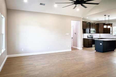 Unfurnished living room with hardwood flooring, lofted ceiling, and ceiling fan