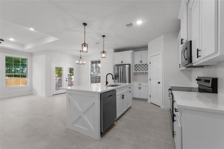 Kitchen featuring a kitchen island with sink, light tile patterned flooring, appliances with stainless steel finishes, and decorative backsplash