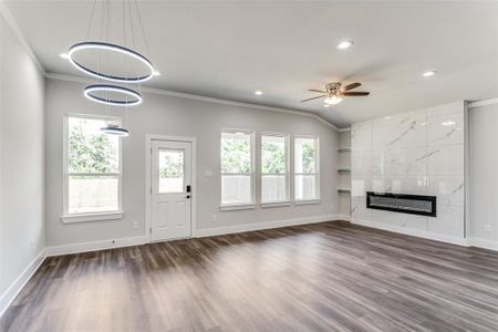 Unfurnished living room with dark hardwood / wood-style floors, a tiled fireplace, and a wealth of natural light