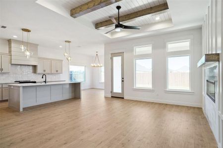 Kitchen with wooden ceiling, a center island with sink, hanging light fixtures, light wood-type flooring, and beamed ceiling