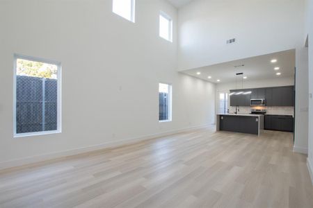 Unfurnished living room featuring a towering ceiling and light hardwood / wood-style floors