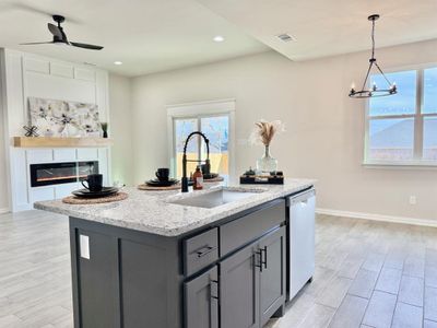 Kitchen with dishwasher, sink, gray cabinetry, a kitchen island with sink, and light stone counters