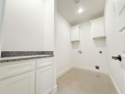 Laundry area featuring visible vents, baseboards, cabinet space, and electric dryer hookup