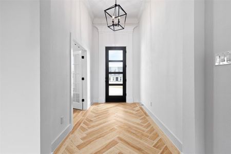 Doorway featuring light parquet flooring and a chandelier