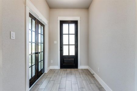 Doorway to outside featuring french doors, light wood-type flooring, and plenty of natural light