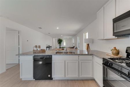 Kitchen featuring black appliances, light hardwood / wood-style floors, sink, and white cabinets