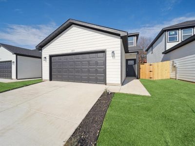 View of front of home featuring a front lawn, an outdoor structure, and a garage