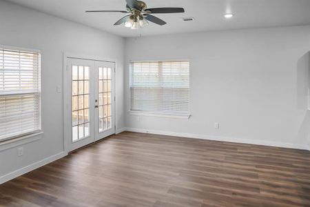 Spare room featuring dark wood-type flooring, plenty of natural light, french doors, and ceiling fan