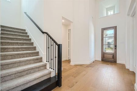 Entrance foyer with light hardwood / wood-style floors and a high ceiling