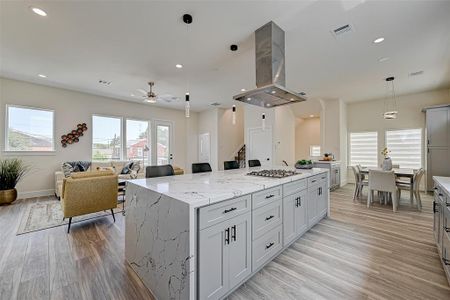 This photo showcases a modern, open-concept living space with a spacious kitchen featuring a large island and sleek cabinetry. The room is bright with natural light from multiple windows, and there's a cozy living area. The dining area is adjacent, offering a seamless flow for entertaining.