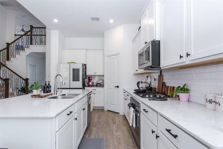 Kitchen with appliances with stainless steel finishes, white cabinetry, a kitchen island with sink, and ceiling fan