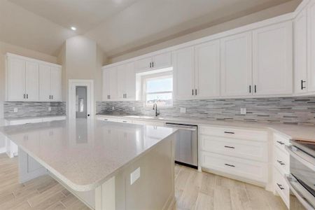 Kitchen with dishwasher, lofted ceiling, white cabinets, and a center island