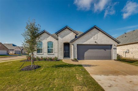 French country home featuring a front lawn and a garage