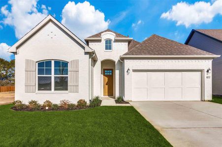 French country inspired facade with a front lawn and a garage