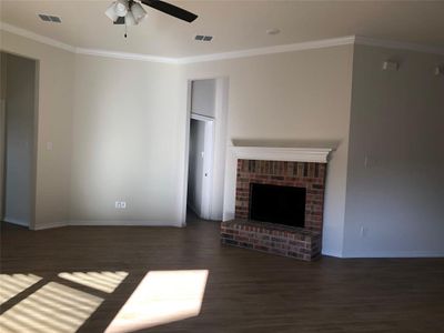 Unfurnished living room with dark hardwood / wood-style flooring, ceiling fan, and crown molding