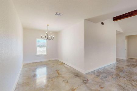 Unfurnished room featuring a notable chandelier and vaulted ceiling with beams