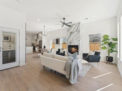 Living room with baseboards, visible vents, light wood-style floors, a fireplace, and recessed lighting