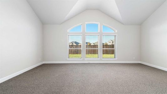 Carpeted spare room with vaulted ceiling