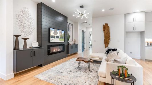 Living room with an inviting chandelier, a fireplace, and light wood-type flooring