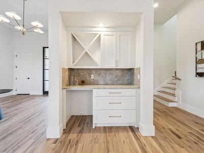 Kitchen featuring white cabinets, hanging light fixtures, decorative backsplash, light hardwood / wood-style floors, and a chandelier