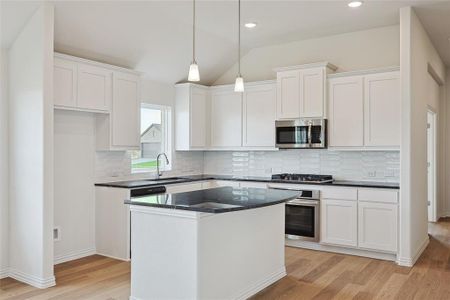 Kitchen featuring light wood-type flooring, a kitchen island, stainless steel appliances, and white cabinets