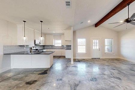 Kitchen with dark countertops, visible vents, white microwave, open floor plan, and stainless steel range with electric cooktop