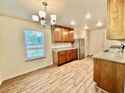 Kitchen featuring light hardwood / wood-style flooring, stainless steel fridge, sink, pendant lighting, and a notable chandelier