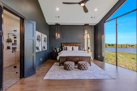 Bedroom with ceiling fan, wood-type flooring, lofted ceiling, access to outside, and a water view