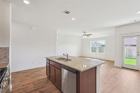 Kitchen with ceiling fan, wood-type flooring, sink, an island with sink, and appliances with stainless steel finishes