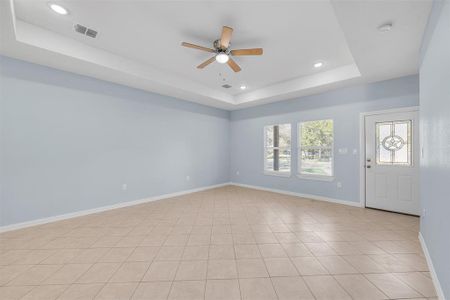 Unfurnished room featuring light tile patterned floors, a raised ceiling, and ceiling fan