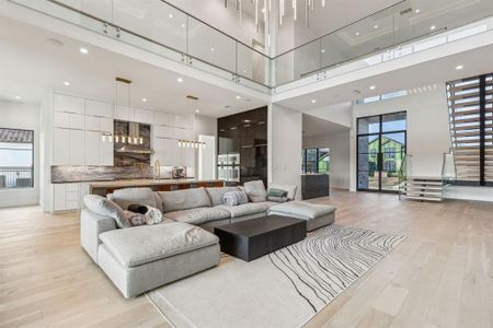 Living room featuring sink, a high ceiling, and light hardwood / wood-style flooring