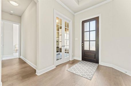 Entrance foyer featuring light hardwood / wood-style floors, ornamental molding, and french doors