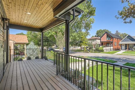 Inviting covered front porch has wrought iron railing and cedar accents, recessed lighting setting a welcoming tone.