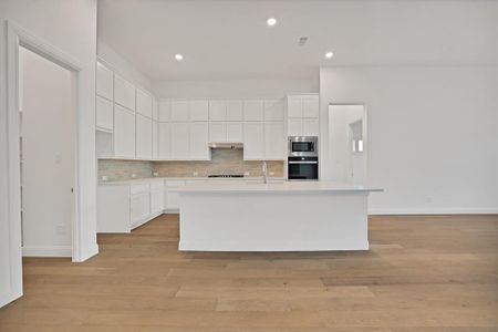 Kitchen featuring tasteful backsplash, a kitchen island with sink, white cabinetry, and appliances with stainless steel finishes