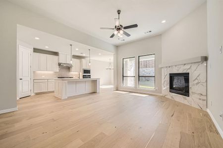 Kitchen featuring white cabinets, a kitchen island with sink, stainless steel microwave, and light hardwood / wood-style floors