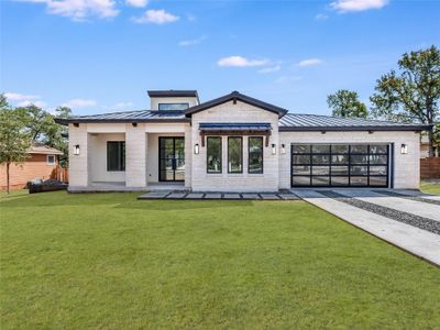 Modern with a front yard, metal roof, and concrete driveway