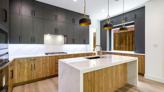 Kitchen featuring pendant lighting, a kitchen island with sink, light hardwood / wood-style flooring, decorative backsplash, and light stone counters