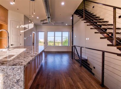 Kitchen with light stone counters, dark wood-type flooring, and pendant lighting