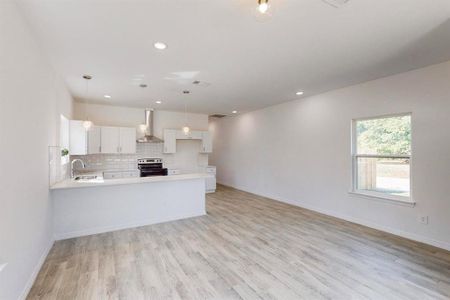 Kitchen with white cabinets, decorative light fixtures, light hardwood / wood-style floors, stainless steel range with electric stovetop, and wall chimney range hood