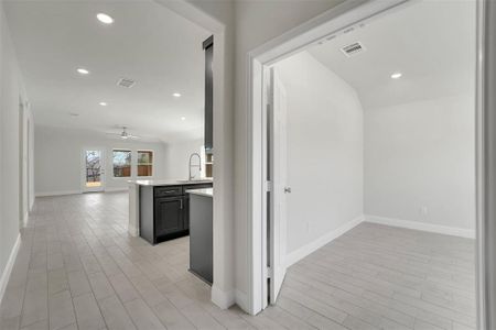 Hallway with light wood-style floors, visible vents, a sink, and recessed lighting