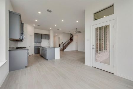 Kitchen featuring a center island with sink, gray cabinets, backsplash, sink, and ceiling fan