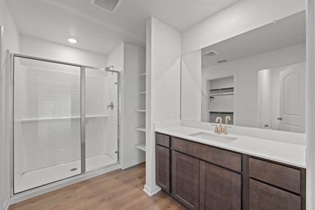 Bathroom with vanity, wood-style flooring, and a shower with shower door