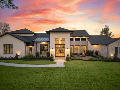 Modern two-story home featuring a triple garage, expansive driveway, and elegant exterior lighting. Set against a stunning sunset sky, the property offers a luxurious and welcoming ambiance.