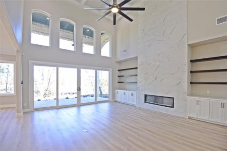 Unfurnished living room featuring a fireplace, a high ceiling, and light hardwood / wood-style floors