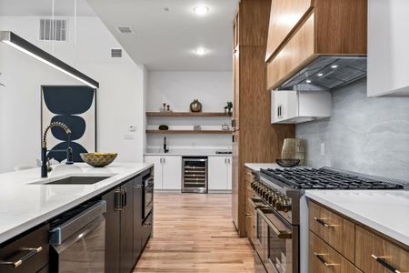 Kitchen with wine cooler, sink, custom exhaust hood, appliances with stainless steel finishes, and backsplash