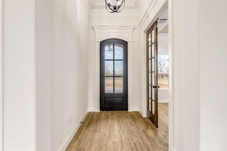 Doorway to outside with a chandelier, light hardwood / wood-style flooring, crown molding, and french doors